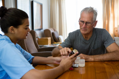caregiver guiding senior man in taking his medicine